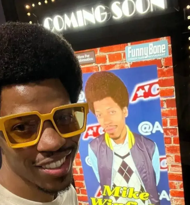 Mike E. Winfield in front of his poster. (Source: Instagram)
